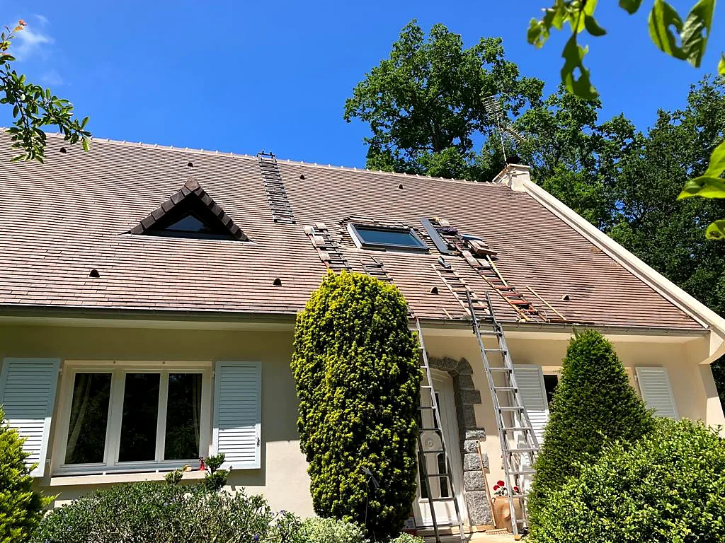 Travaux autour d'une fenêtre de toit sur une toiture en tuiles